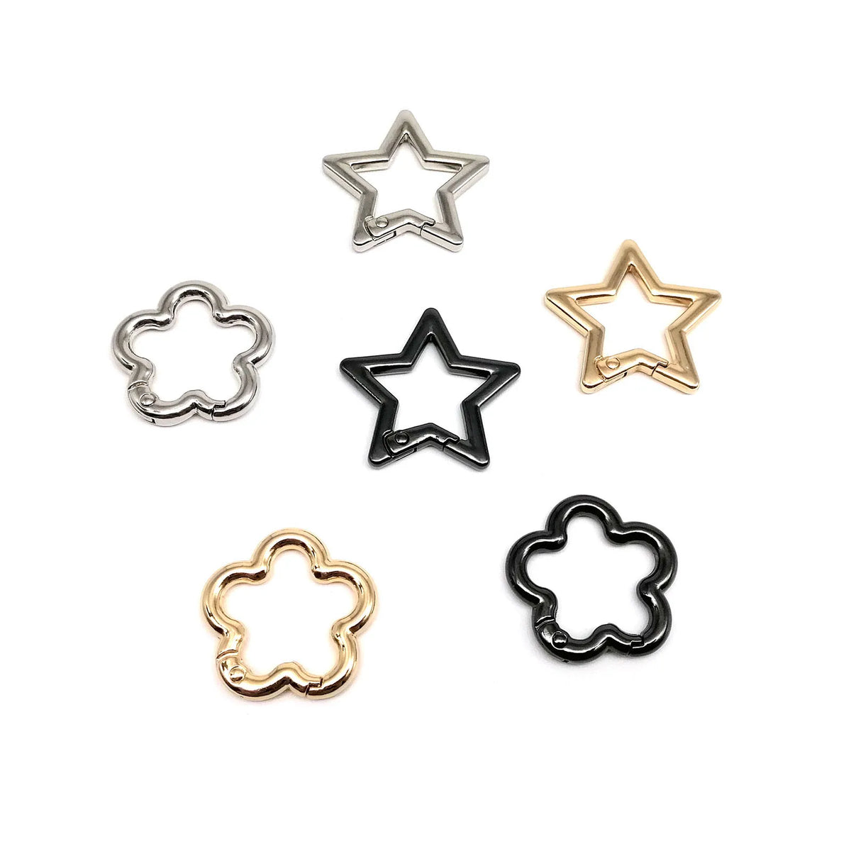 Une collection de cinq attaches métalliques en forme d'étoile et de fleur.