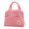 A pink insulated lunch bag for kids with a pink handle and a cute face design.