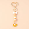Gold and white starfish keychain featuring pearl accents and a decorative bow.