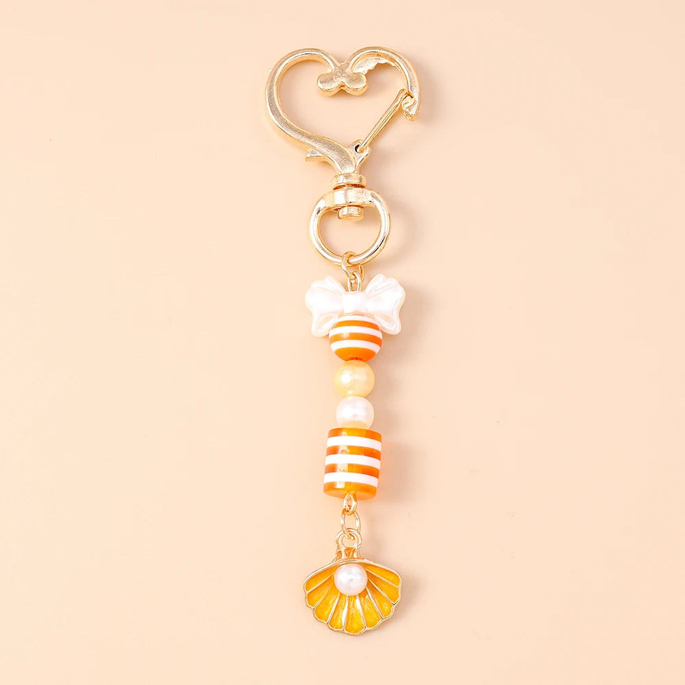 Gold and white starfish keychain featuring pearl accents and a decorative bow.