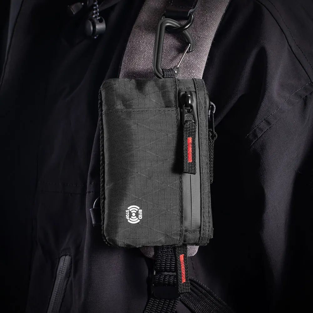 Black RFID blocking travel wallet attached to a gray jacket with a carabiner clip