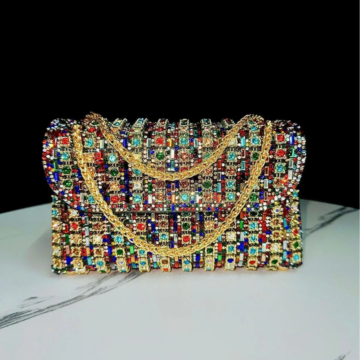 A luxury rhinestone evening clutch bag featuring intricate gold detailing and colorful gemstone embellishments.