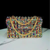 An elegant rhinestone leather evening clutch bag featuring intricate gold detailing and colorful gemstones.