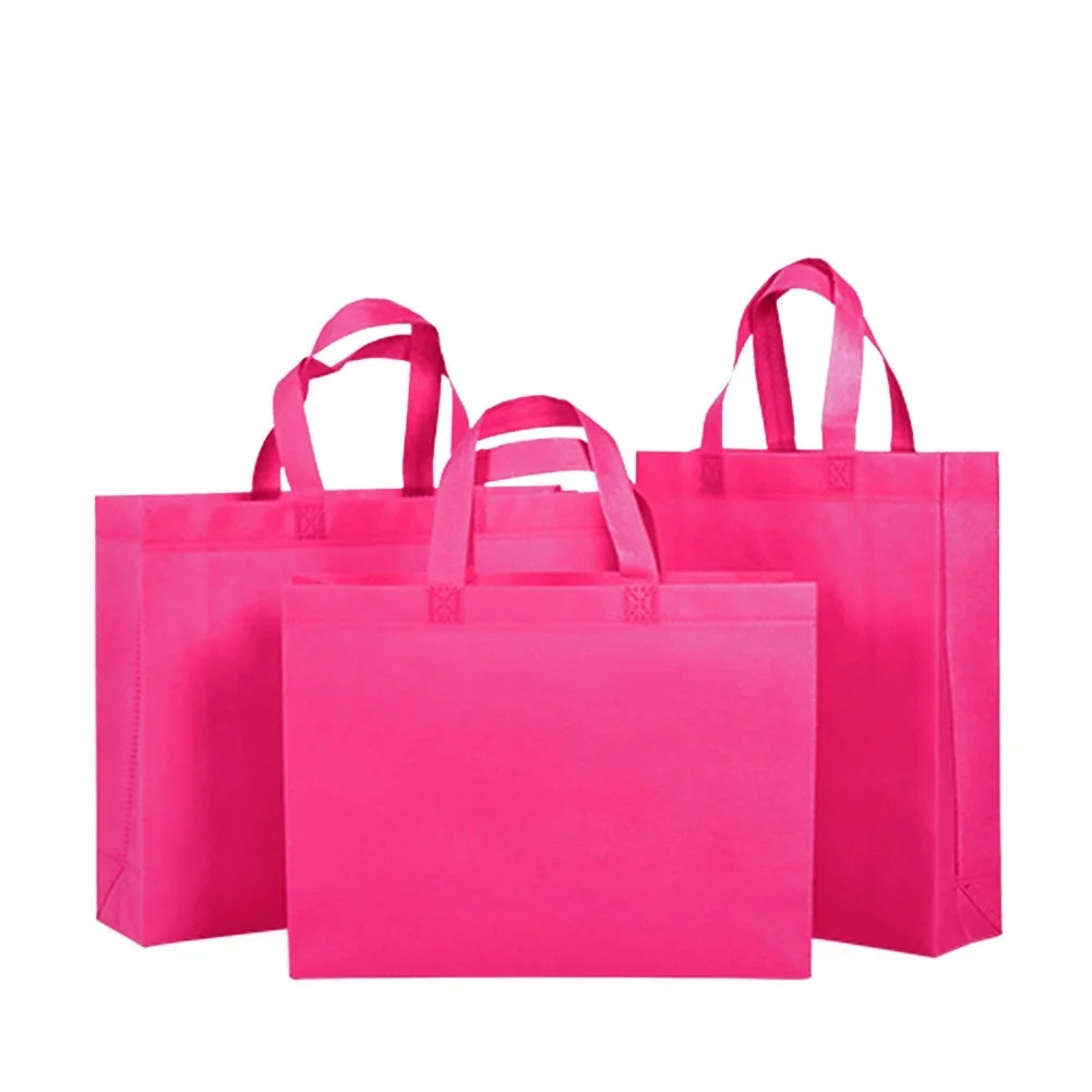 Ein Stapel leuchtend pinker nichtgewebter Einkaufstaschen mit Henkeln.