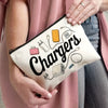 A beige travel organizer pouch holding various electronic chargers and cables, held by a person in a pink cardigan.