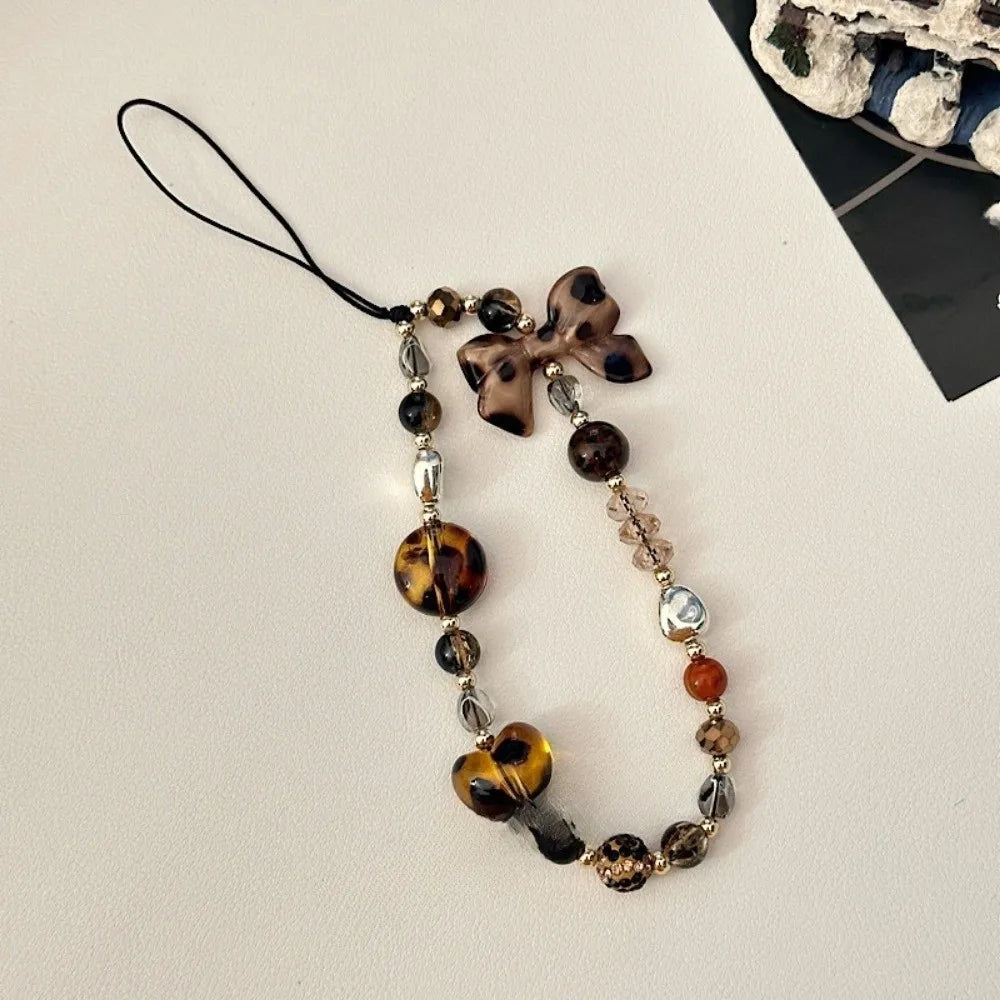 A necklace featuring heart-shaped beads in leopard print and silver accents on a black cord.