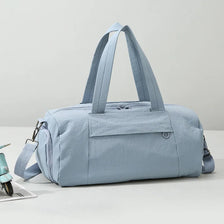 A light blue Oxford gym duffel bag with padded straps resting on a white surface.