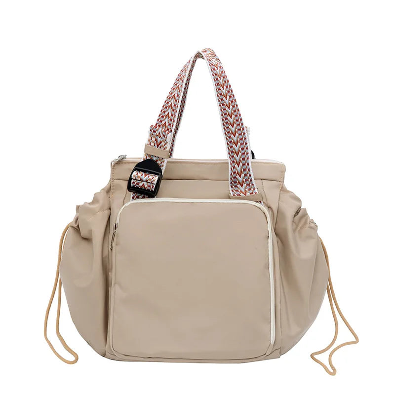 A beige nylon shoulder bag with patterned straps and a flap closure.