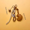 A brown leather croissant shaped keychain with a lanyard and pendant on a beige background.