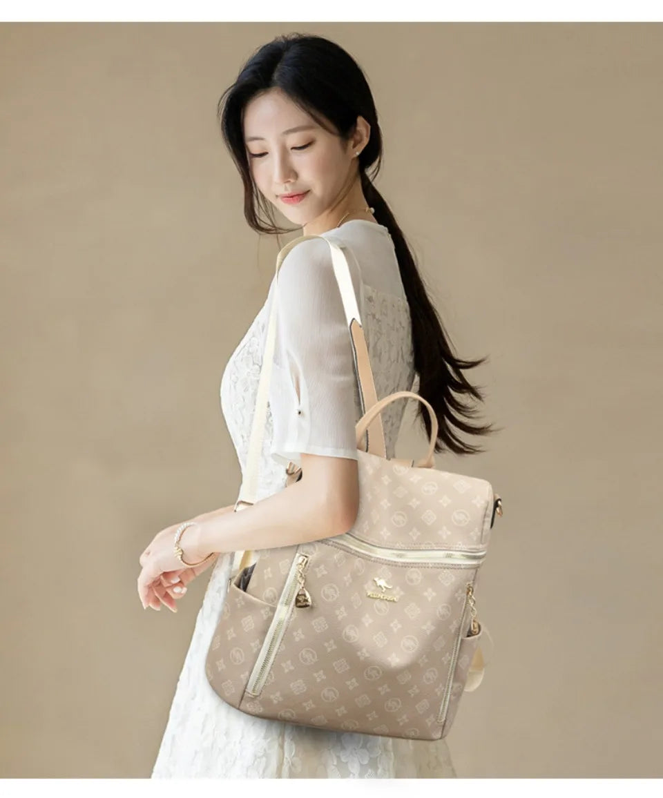 A woman wearing a cream-colored dress holds a beige genuine leather women's backpack.