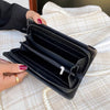 A black punk style long leather wallet is shown open on a light fabric surface.