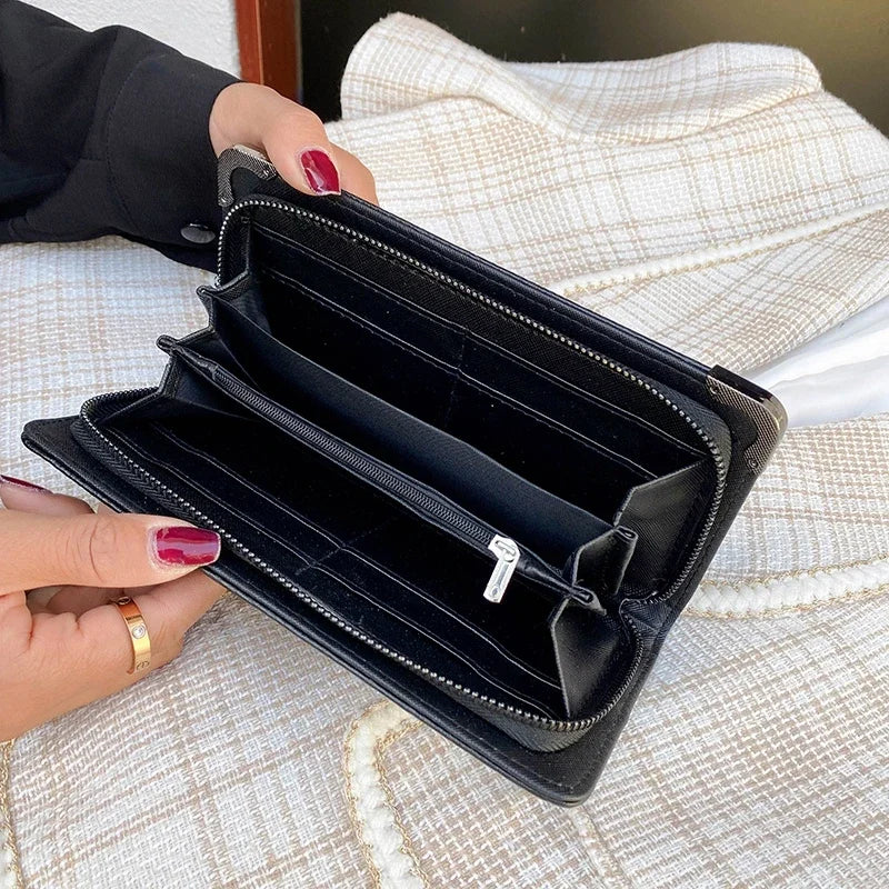 A black punk style long leather wallet is shown open on a light fabric surface.