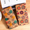 A close-up of a bohemian wood-grain leather wallet with multiple card slots featuring colorful floral patterns.