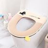 A beige plush waterproof toilet seat cover with a black dog design and a yellow accent is shown on a white toilet.