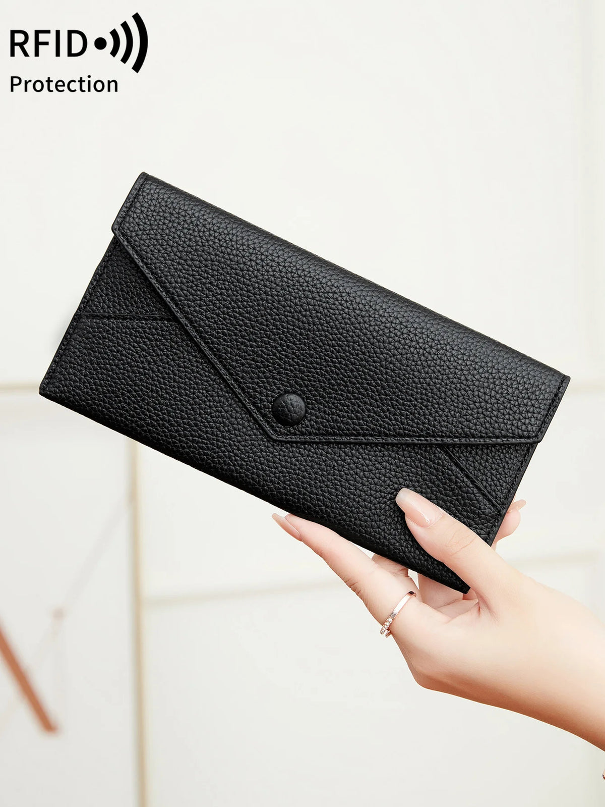 Eine Hand hält eine schwarze minimalistische Kunstleder-Münzgeldbörse mit Riegelverschluss.