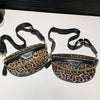 Leopardenmuster-Crossbody-Bauchtasche mit schwarzem Riemen und goldfarbenem Verschluss auf weißem Untergrund.