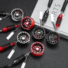 A collection of black and red alloy wheel hub brake disc rearview mirror pendants displayed on a dark surface.