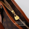 Close-up of a brown leather crossbody bag featuring gold hardware and a textured print.