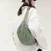 A woman wearing a light gray hoodie and black hat carrying an olive green corduroy waist pack.