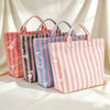 A collection of striped pink, green, and blue waterproof PVC shoulder tote bags displayed against a white draped background.