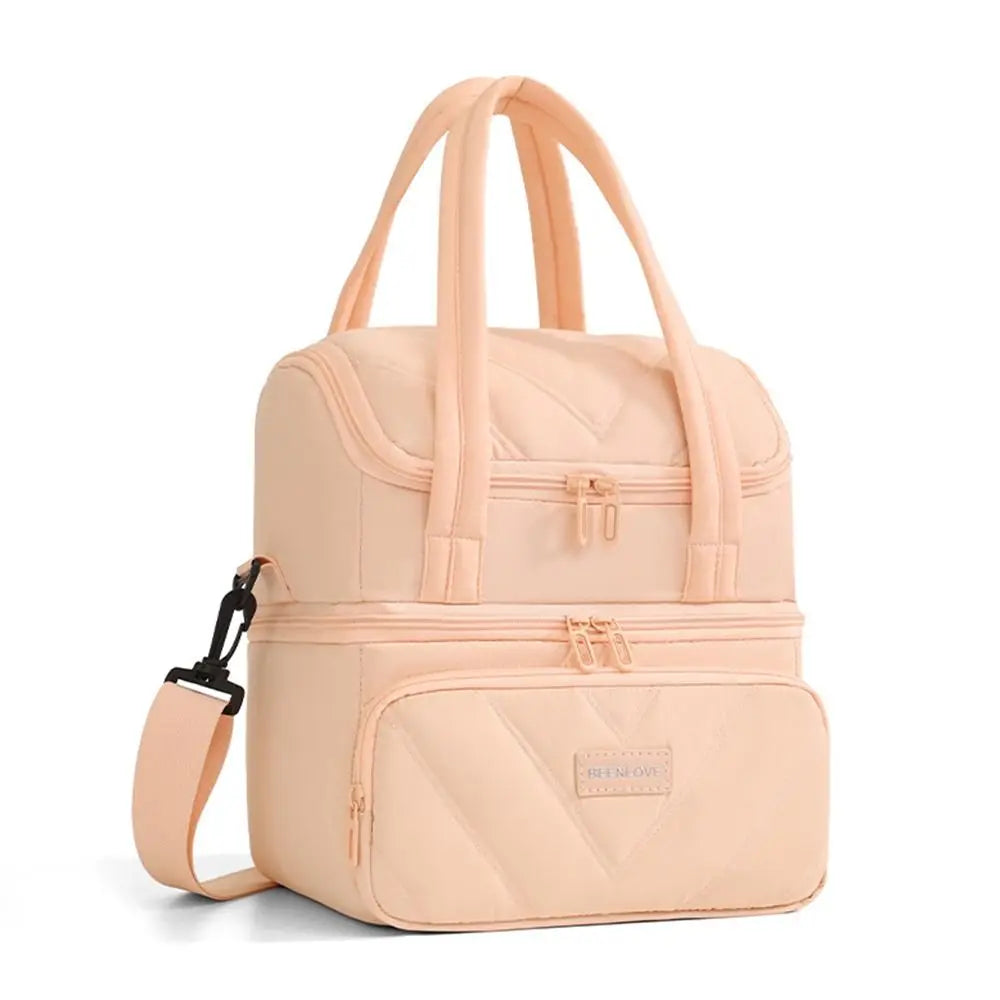 Una bolsa de almuerzo aislada color melocotón claro con textura acolchada y correas rosas.