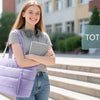 A smiling young woman holds a purple quilted multi-compartment tote bag in an outdoor school setting.
