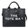 Sac cabas de luxe noir designer avec quincaillerie dorée, vue de face.
