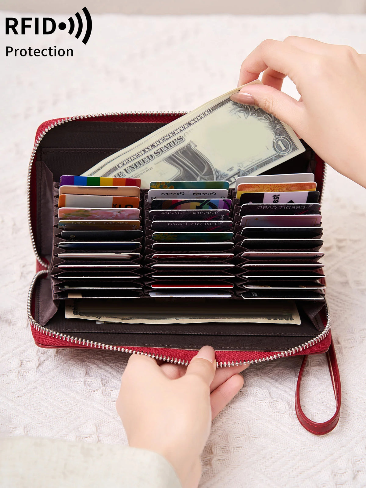 A red wallet with a zipper closure is shown open, displaying various cards and cash protected by RFID shielding.