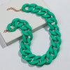 A green matte acrylic chain necklace with a gold-tone clasp is displayed on a white box.