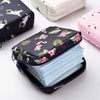 A black compact pouch filled with light blue sanitary pads is shown next to a pink storage pouch.