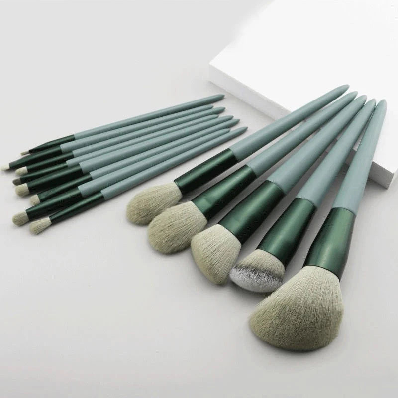 Un juego de trece brochas de maquillaje profesionales con mangos cónicos y cerdas suaves, dispuestas en diagonal sobre una su