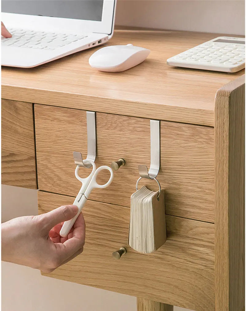 A hand is using a white hook rack to open a cabinet door, showing the multi-purpose hook rack for cabinet doors.