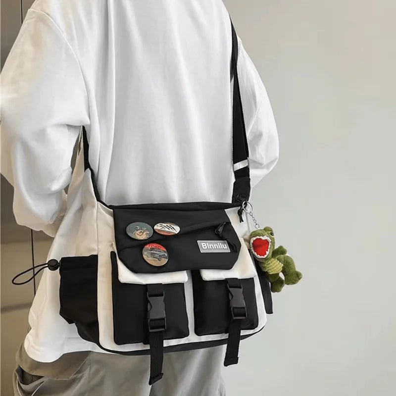 Una persona de manga larga blanca sostiene un bolso cruz de nylon blanco y negro con un peluche verde.