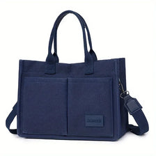 Bolso tote de lona azul marino con detalles de cuero, visto desde el frente.