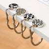 A set of round metal bag hangers with leopard print tops displayed on a white surface.