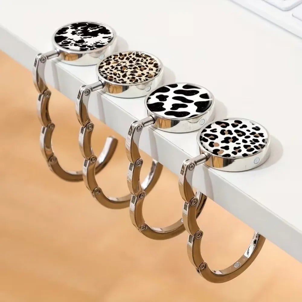A set of round metal bag hangers with leopard print tops displayed on a white surface.