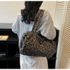 A person is shown from the back carrying a leopard print canvas tote bag with an adjustable shoulder strap.