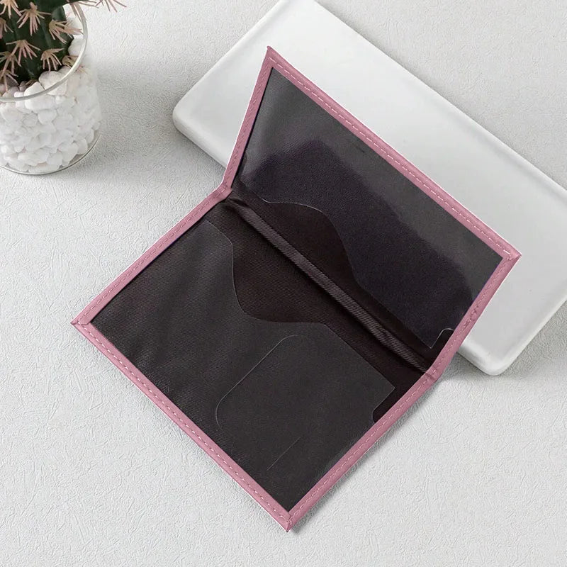 Une housse de passeport en cuir PU rose est ouverte sur un plateau blanc, montrant un intérieur violet foncé.