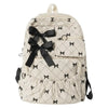 A cream-colored corduroy backpack with a black bow print design and pocket details.