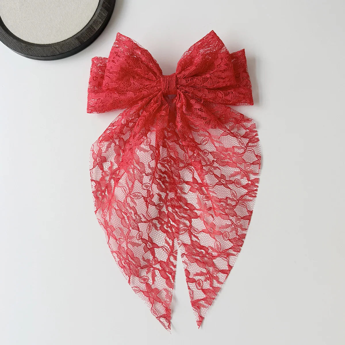 Leuchtend rotes Spitzenbindchen in einer verzierten Schleife, präsentiert auf einer weißen Oberfläche.