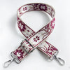 A close-up of a pink and white floral jacquard strap for an adjustable crossbody bag.