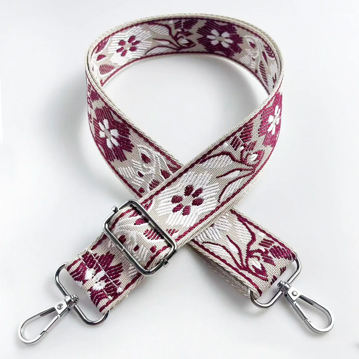 A close-up of a pink and white floral jacquard strap for an adjustable crossbody bag.