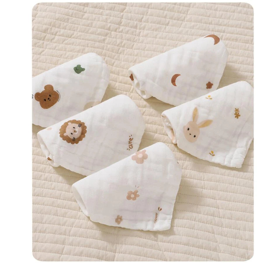 A collection of soft cotton muslin baby burp cloth towels in white with subtle floral and animal embroidery.