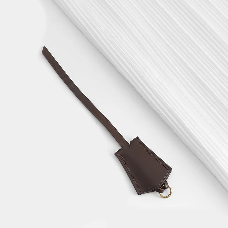 A dark brown genuine vachetta leather bag strap is shown against a white background.