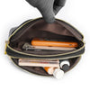 A hand is opening a brown PU leather trendy shoulder crossbody bag revealing a smartphone and some small items inside.