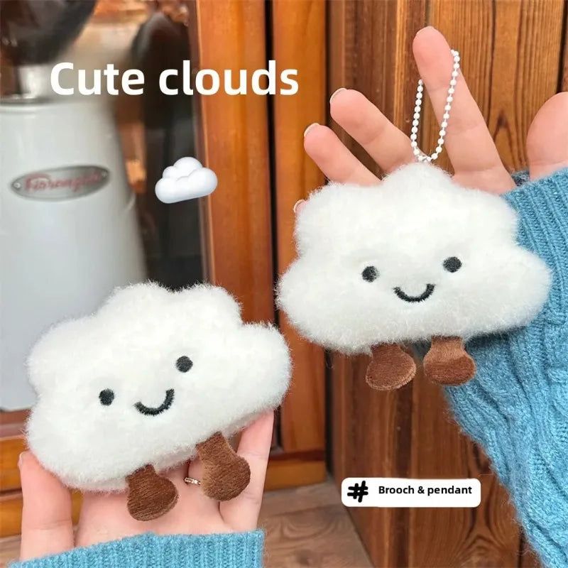 White fluffy cloud shaped plush keychains and brooch pins held in a hand