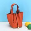Orangefarbener, echter Leder-Eimer-Tasche mit Klappverschluss auf weißem Untergrund.