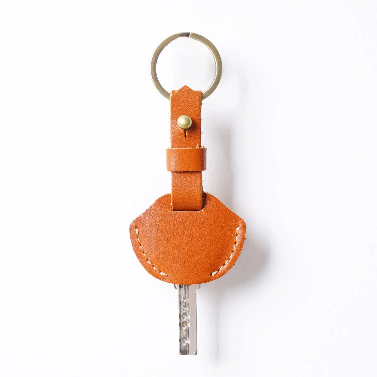 A genuine leather key fob cover with a keyring ring and a metal keychain.