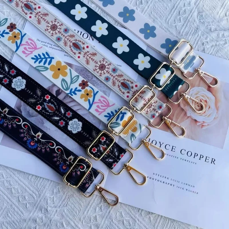 A collection of colorful embroidered nylon bag straps featuring floral and geometric patterns on a white background.