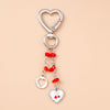 Silver heart-shaped keychain with a chain and red beads, featuring a small heart charm.